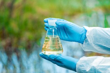 a flask with water from a lake in the hands of a environmentalist chemist close-up