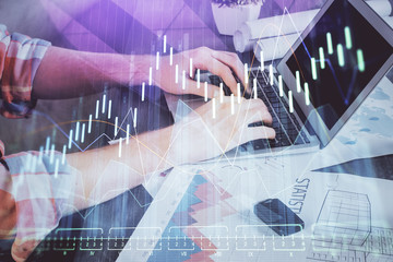 Double exposure of stock graph with businessman typing on computer in office on background. Concept of hard work.