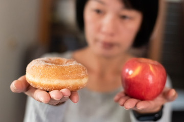 woman hold an apple and donuts