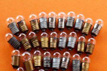 Light bulbs with textured gold bronze and silver surface. Vintage lamps collection macro view. Orange background, shallow depth of field photo.