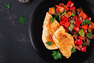 Grilled chicken fillets and sweet pepper on black plate. Top view, copy space