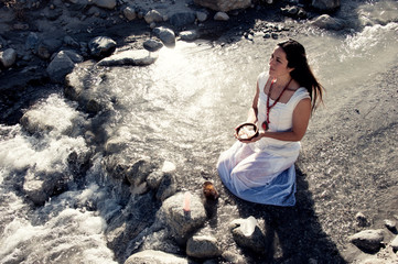 Light worker woman with crystal offering in the flowing waters of a wild river. 