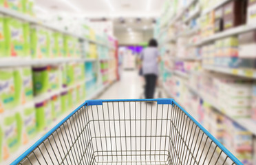 Supermarket aisle with empty green shopping cart