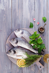 Raw dorado fish with green herbs cooking on cutting board. Top view