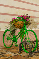 decorative flower bed in the form of a green-colored bicycle
