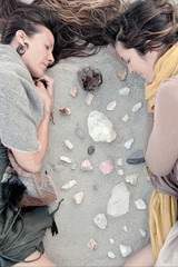 Two peaceful women meditating on the earth with healing stone crystals. 