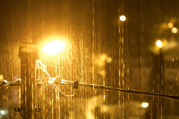Night rain spray in the light of a street lamp. The concept of water-repellent surface, light and...