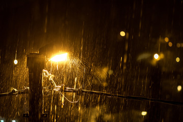 Night rain spray in the light of a street lamp. The concept of water-repellent surface, light and...