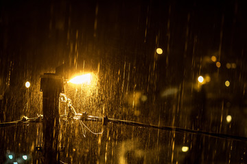 Night rain spray in the light of a street lamp. The concept of water-repellent surface, light and...