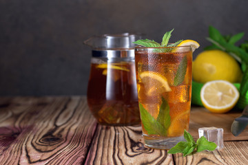 Glass of iced tea with mint and lemon. Cold drink. Rustic style