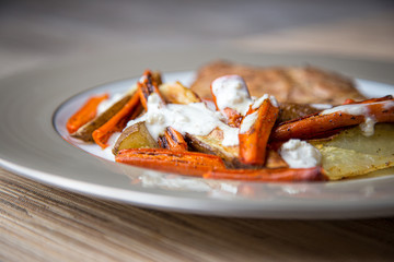A simple, inexpensive meal: grilled chicken, roasted carrots and potatoes with a garlic sour cream...