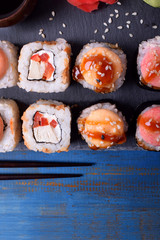 Sushi rolls assortment, wasabi, marinated ginger and soy sauce served on slate plate
