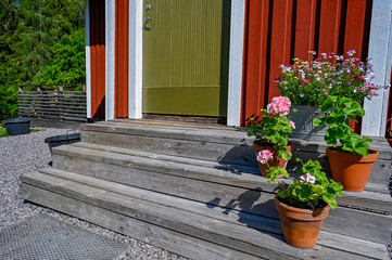 flowers on stairs infront of a red wooden cabin
