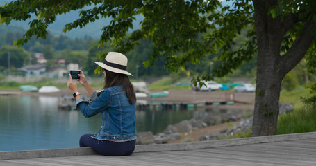 Woman take photo and sit on lake side