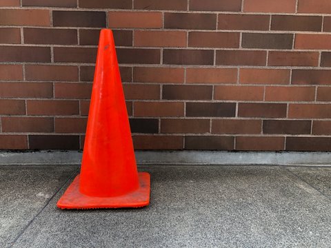 traffic cone next to a brick wall