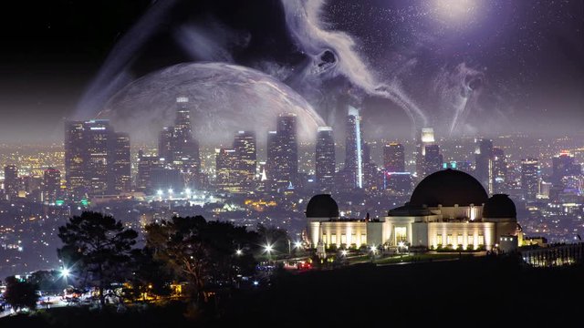 Giant moon with dramatic sky rising above Griffith Observatory and Los Angeles skyline