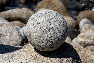 Fototapeta na wymiar Background image. Natural marble ball on the rocky beach