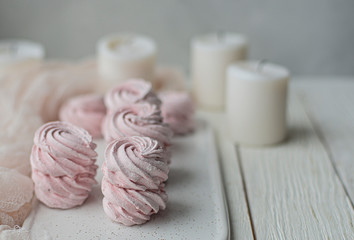 homemade Marshmallow zephyr with candles on a white plate on a light wooden table. Pink sweet homemade marshmallow or marshmallow. Colorful meringues on a white background. dessert