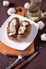 Baked potato with onions and spices on a white dish on the background of a wooden table