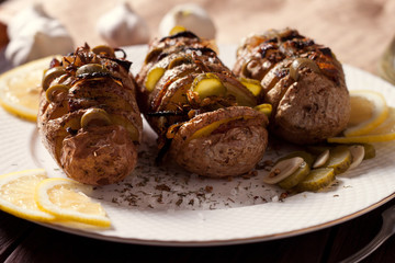 Baked potato with onions and spices on a white dish on the background of a wooden table