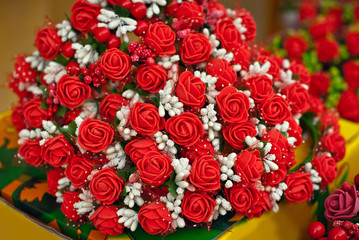 Bouquets of artificial flowers are sold at the fair. Corollas of colored small flowers. Closeup of...