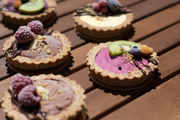 Raw vegan tartlets on the wooden table. Healthy desserts, close up