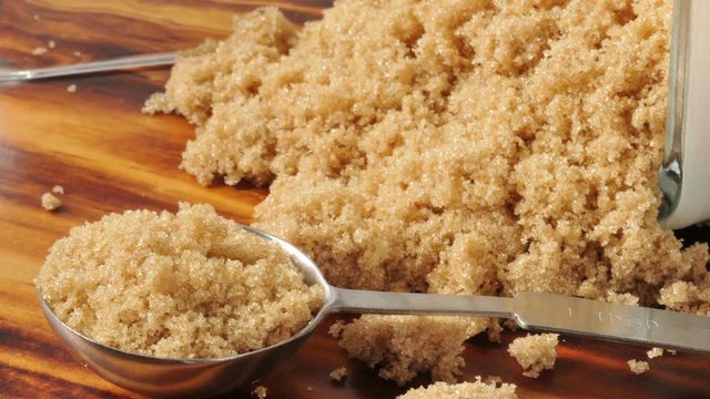 Tablespoon of brown sugar with more spilling out of the canister