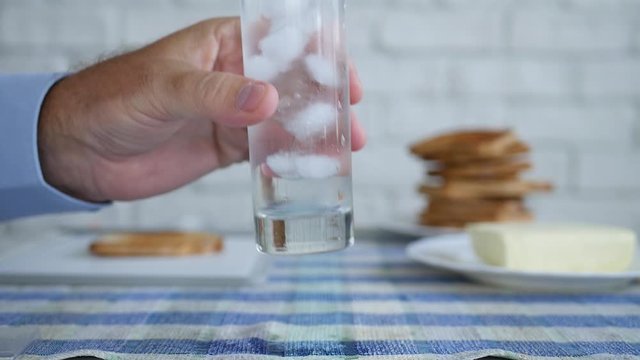 Slow Motion with Hand Taking from the Table a Glass with Water and Cube Ice