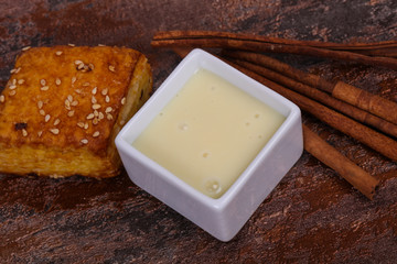 Condenced milk in the bowl with sinnamon and pastry