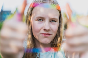the  teen girl looks  at camera through the colored frame in summer time. 