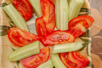 Fresh cucumbers and tomatoes are cut and cleaned from the skin lying on the plate