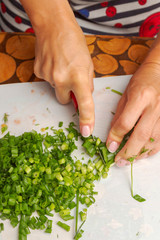 Cutting fresh greens and green onions on a white cutting Board