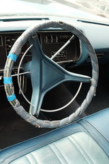 Ausgebessertes Dreispeichen Lenkrad einer amerikanischen Limousine der Sechzigerjahre mit blauem...