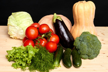 View of various fresh lush clean vegetables, grown in local organic greenhouses with use of natural eco fertilize, black background. Studio shot, close up view.