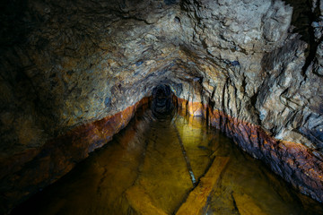 Dark creepy dirty flooded abandoned mine tunnel