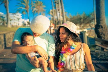 Happy young family walking down the road outside. Family  spending time together. Happy Multiethnic Family in the summertime. Father Hugging Her Baby . Image
