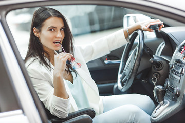 Attractive young woman driving a car. Fancy woman in the automobile. Rich adult female in the car. Confident woman.
