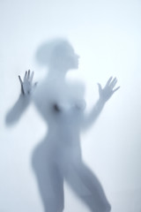 Beautiful slim woman taking a hot shower while standing behind the blurred glass. close up photo. lifestyle, sexuality, seduxtion concept.