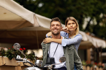 Happy couple of tourist travelers around city with motorbike scooter