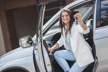 Young attractive woman just bought a new car. female holding keys from new automobile.