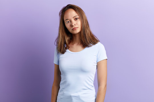 Young beautiful brown-haired woman with pigmented skin, chloasma wearing white T-shirt. close up portrait. isolated blue background, studio shot.lifestyle, free time, spare time