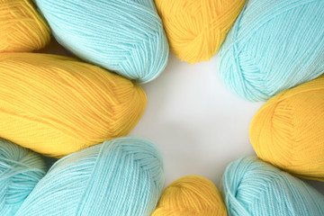Mint and yellow acrylic yarn on a white background, lined up in a circle, with copyspace. Beautiful yarn for knitting baby clothes. For yarn, children's clothing store, flyer design, banner, for site