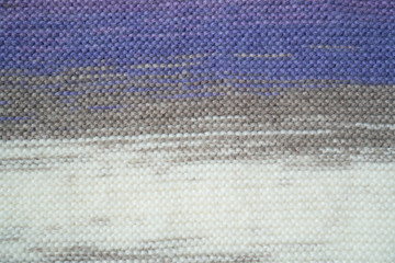 Knitted horizontal textured multicolored fabric on a white background. Fragment of a brown, purple, beige, white color sweater. Texture, close up. For yarn, clothing, needlework store