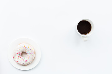 donut and black coffee with copy space. Cup of black coffee with donut on a plate on white table, top view, flat lay. Delicious breakfast.