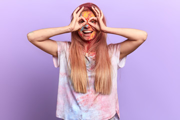 cheerful positive girl looking through imaginable fake glasses, isolated blue background, studio shot.feeling and emotion . girl having fun at the festival