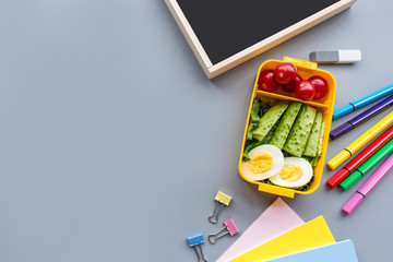 School supplies and lunch box with sandwich and vegetables. Back to school. Healthy eating habits concept - background layout with free text space. Flat lay composition, mockup, top view