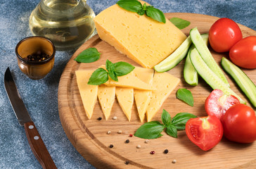 Dutch cheese with cucumbers and tomatoes and basil on a blue background.