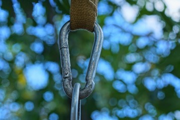 one gray metal carabiner clasp hanging from a harness on the street