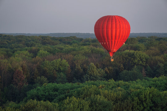 Red Hot Air Balloon In The Sky Above The Trees