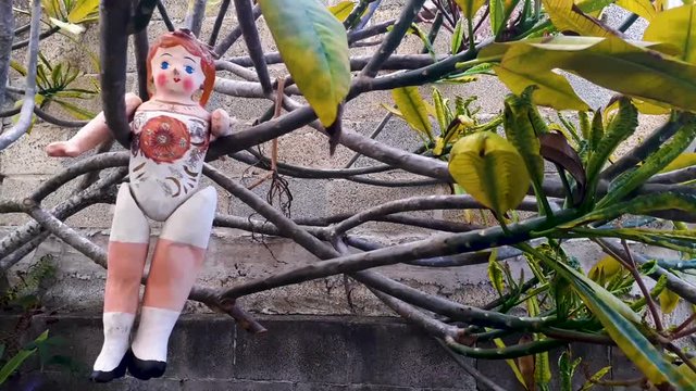vintage style doll, handmade hanging on green tree branches, movement with wind